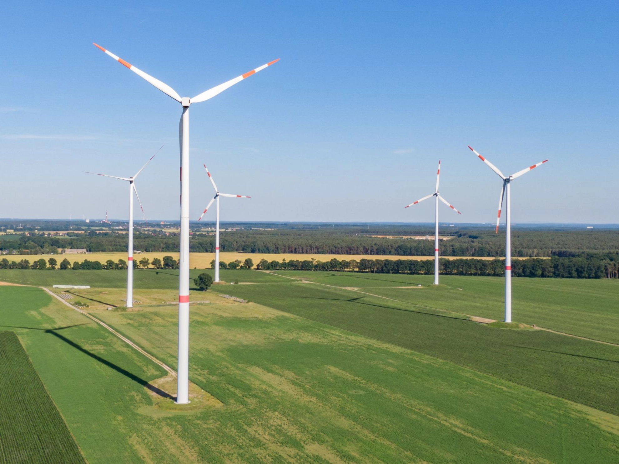 mehrere Windkraftanlagen bei gutem Wetter auf grüner Wiese